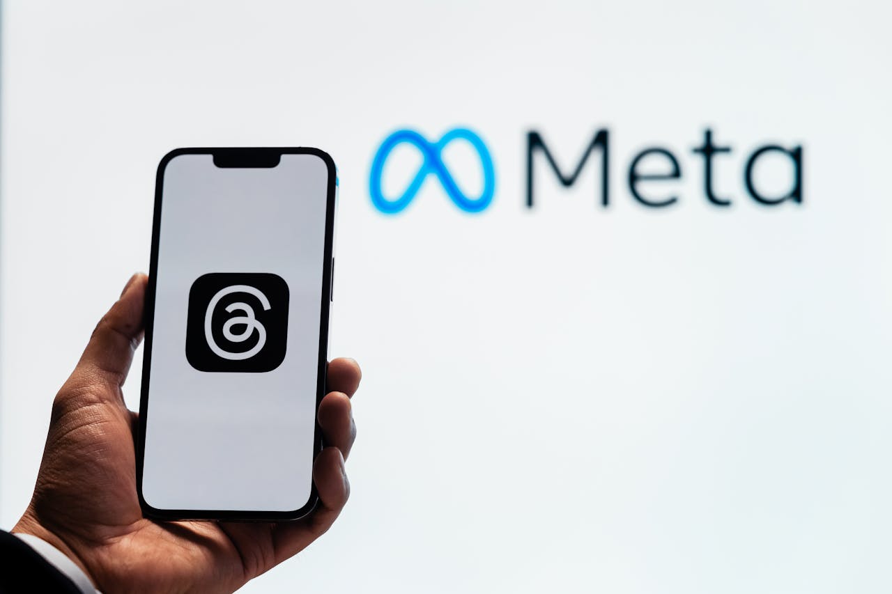 Smartphone showing Threads logo in front of Meta logo during Play AI acquisition news